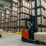 Depozit logistic modern cu stivuitoare care manipulează marfă paletizată