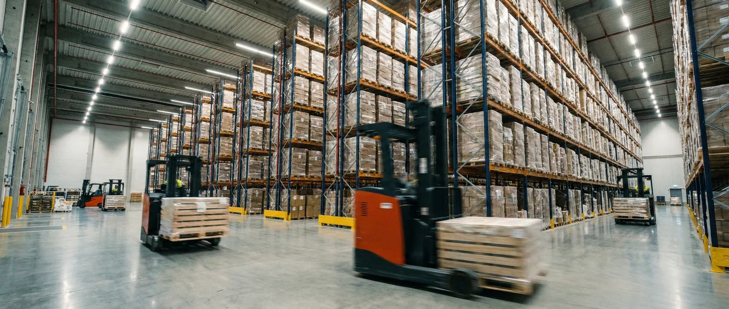 Depozit logistic modern cu stivuitoare care manipulează marfă paletizată