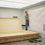 Echipă de logistică a artei manipulând un tablou într-o galerie, demonstrând servicii white glove